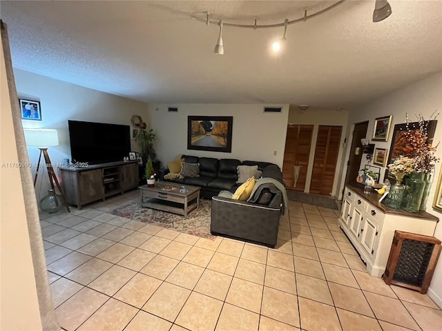 living room with light tile patterned floors, visible vents, and a textured ceiling