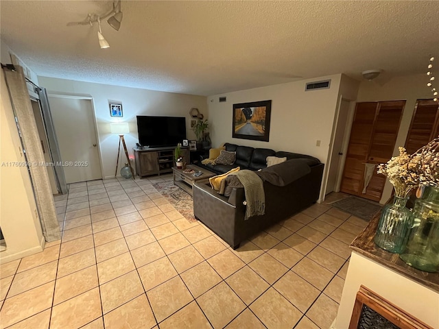 living area featuring visible vents, a textured ceiling, and light tile patterned flooring