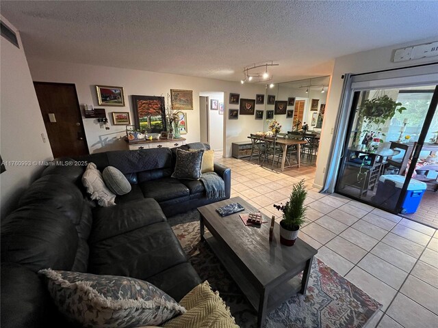living area with light tile patterned flooring, rail lighting, and a textured ceiling