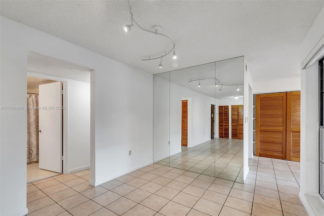 unfurnished room with a textured ceiling and light tile patterned flooring