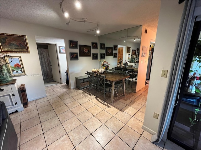 dining room with light tile patterned floors, baseboards, and a textured ceiling