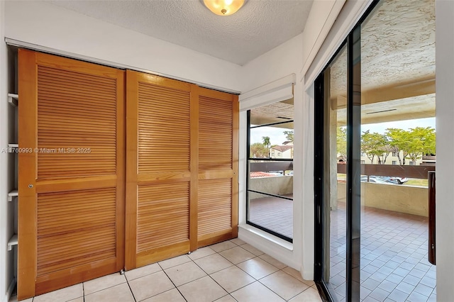doorway to outside featuring plenty of natural light, a textured ceiling, and light tile patterned flooring