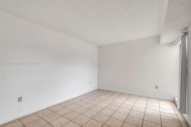 spare room featuring light tile patterned floors and a textured ceiling