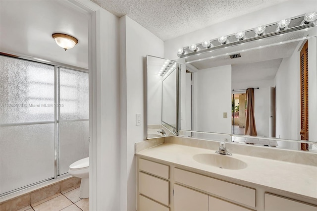 full bath with toilet, a stall shower, a textured ceiling, tile patterned flooring, and vanity