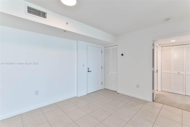 spare room with light tile patterned flooring, baseboards, and visible vents