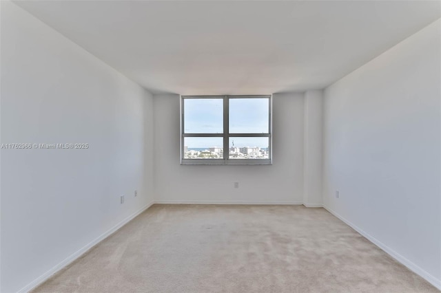 spare room featuring light colored carpet and baseboards