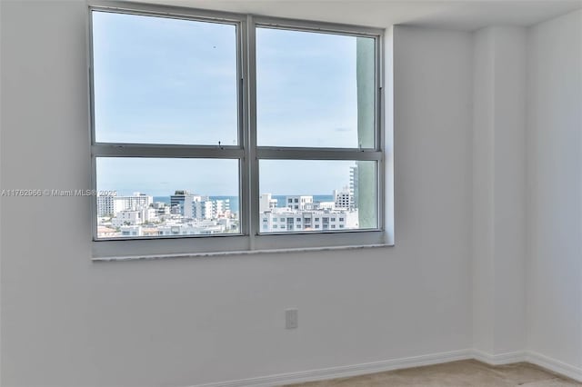 spare room featuring a view of city, carpet, and baseboards