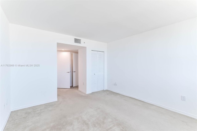 spare room featuring visible vents, light colored carpet, and baseboards