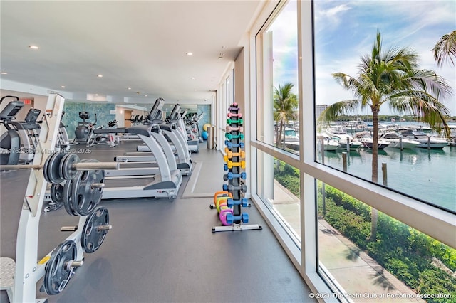 exercise room featuring recessed lighting and a water view