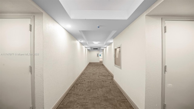 corridor with a textured wall, baseboards, and carpet floors