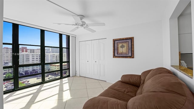 living area with a wall of windows, a view of city, a ceiling fan, and light tile patterned floors