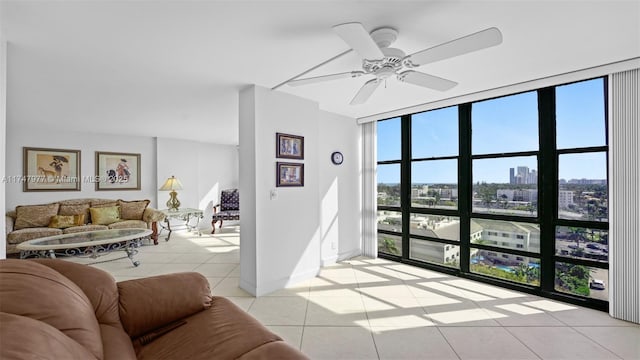 living room featuring a city view, a ceiling fan, expansive windows, light tile patterned flooring, and baseboards