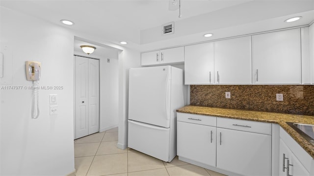 kitchen with visible vents, backsplash, white cabinetry, freestanding refrigerator, and light tile patterned flooring