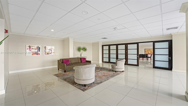 living room featuring tile patterned flooring, visible vents, and a paneled ceiling