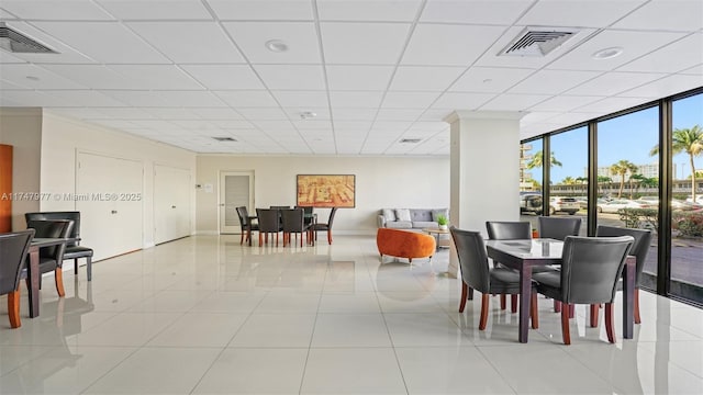 dining space with visible vents, baseboards, floor to ceiling windows, light tile patterned floors, and a paneled ceiling