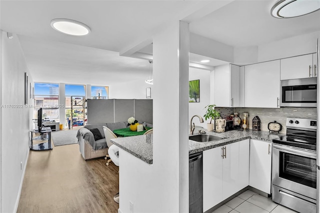 kitchen with a sink, white cabinets, appliances with stainless steel finishes, tasteful backsplash, and open floor plan