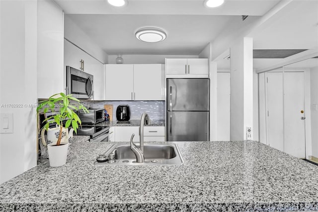 kitchen featuring a sink, light stone counters, tasteful backsplash, appliances with stainless steel finishes, and white cabinets