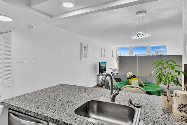 kitchen with light stone counters, dishwasher, and a sink