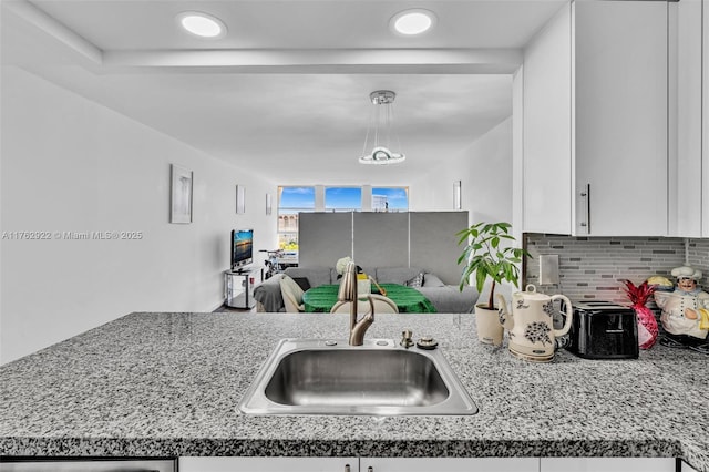 kitchen with decorative backsplash, light countertops, white cabinetry, and a sink