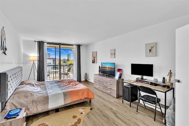 bedroom featuring a wall of windows, wood finished floors, and access to outside