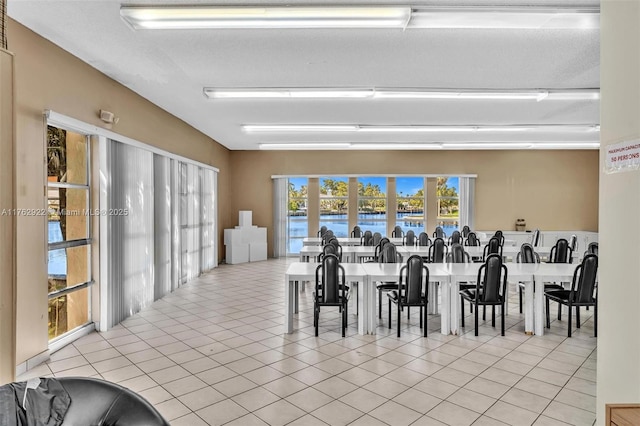 dining space with light tile patterned floors and a water view