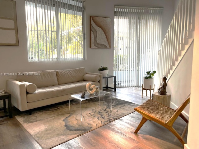 living area featuring plenty of natural light, stairs, and wood finished floors