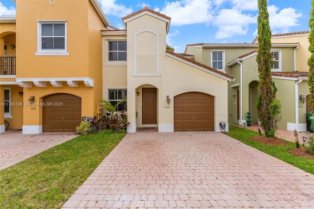 view of front of property featuring stucco siding, decorative driveway, a garage, and a tile roof