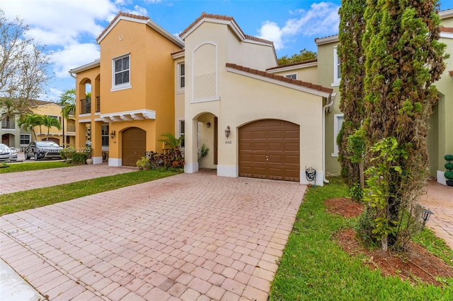 mediterranean / spanish house with stucco siding, a tile roof, decorative driveway, and a garage