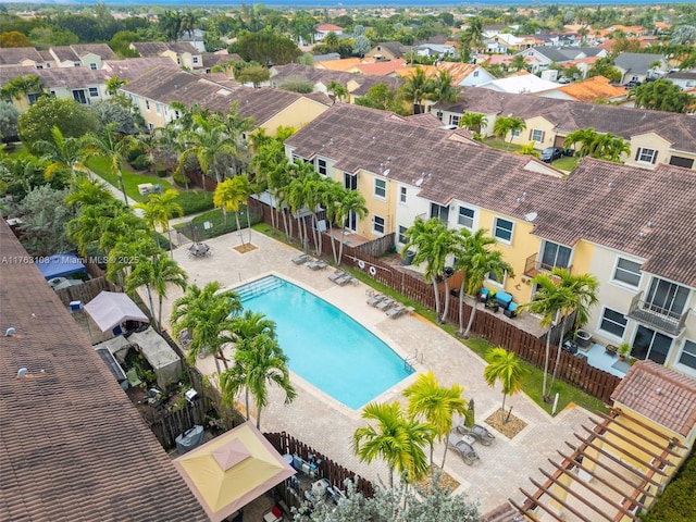 community pool featuring a patio area, fence, and a residential view