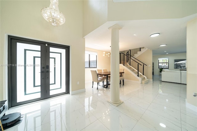 foyer with baseboards, stairs, a notable chandelier, marble finish floor, and ornate columns