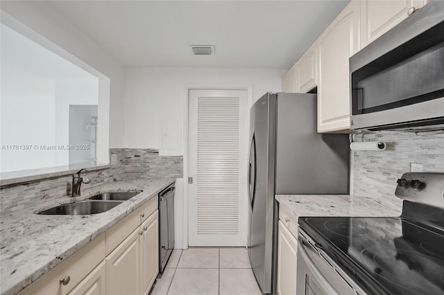 kitchen featuring light tile patterned floors, visible vents, a sink, stainless steel appliances, and tasteful backsplash