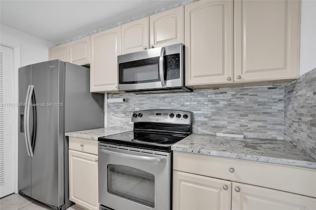 kitchen with backsplash, light stone countertops, appliances with stainless steel finishes, and light tile patterned flooring