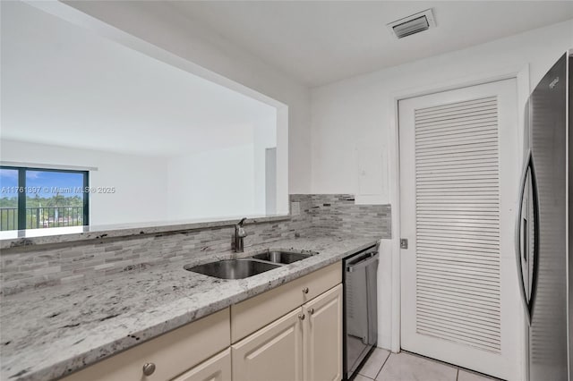 kitchen featuring visible vents, a sink, tasteful backsplash, freestanding refrigerator, and dishwasher