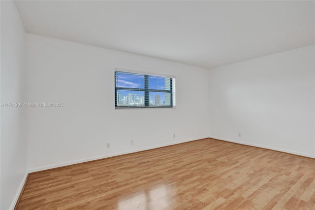 empty room with baseboards and light wood-style floors