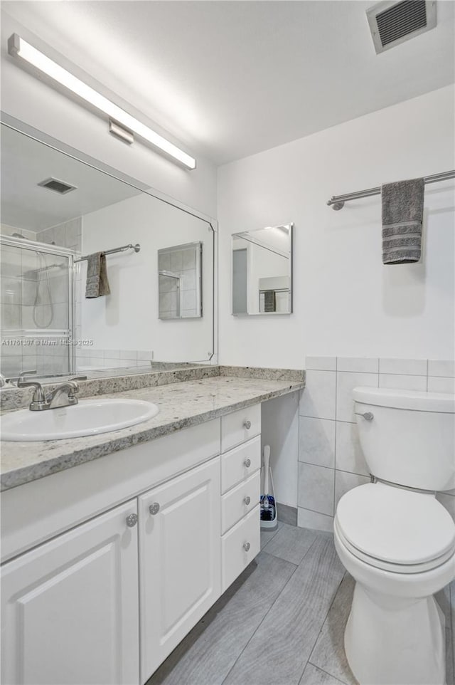 bathroom featuring visible vents, a shower stall, toilet, and tile walls