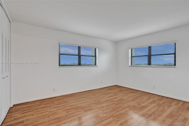 spare room with light wood-type flooring and baseboards