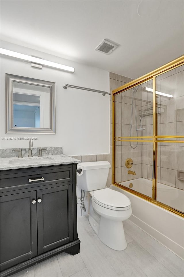 bathroom with visible vents, enclosed tub / shower combo, toilet, and vanity