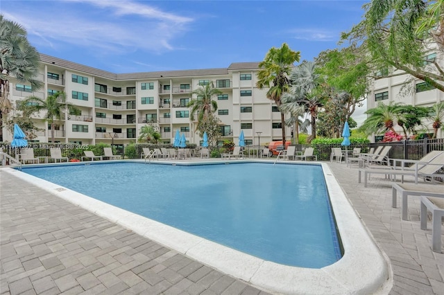 community pool with a patio area and fence