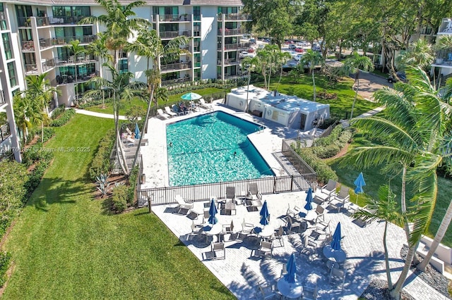 pool featuring a patio, a lawn, and fence