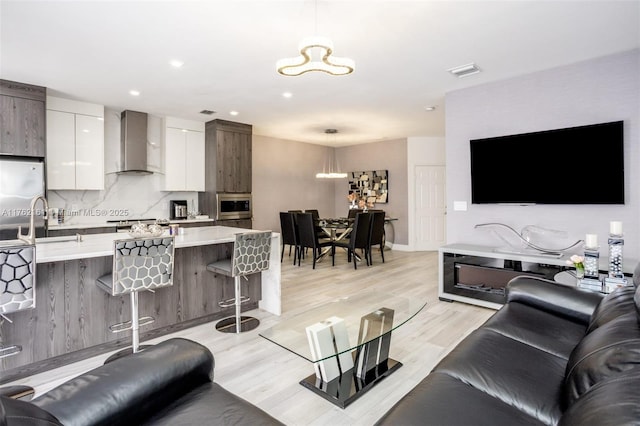 living room featuring recessed lighting, light wood-type flooring, visible vents, and a chandelier