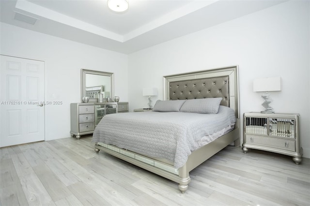 bedroom with a raised ceiling and wood finished floors