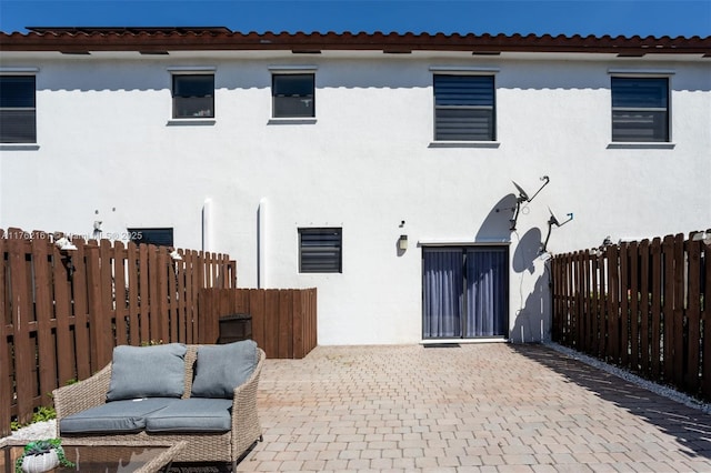 back of house featuring stucco siding, decorative driveway, fence private yard, and a patio area