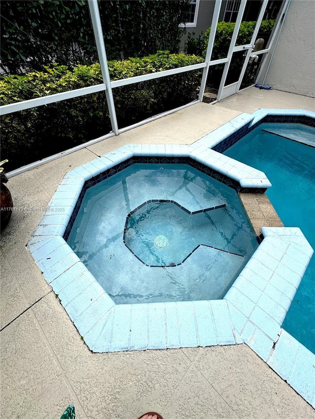 pool featuring a lanai, a patio area, and an in ground hot tub