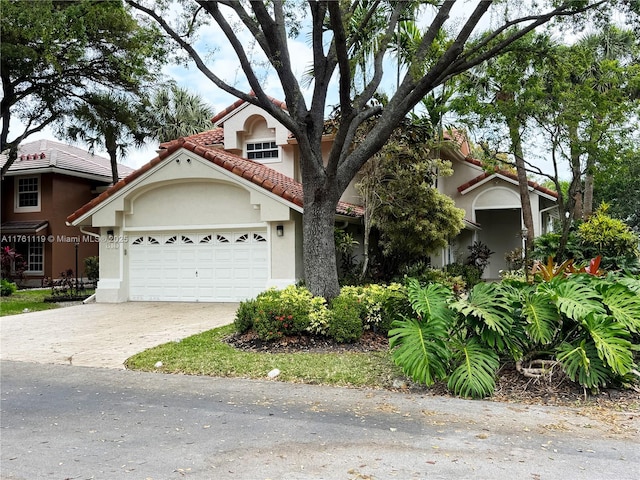 view of front of house with stucco siding, an attached garage, driveway, and a tiled roof