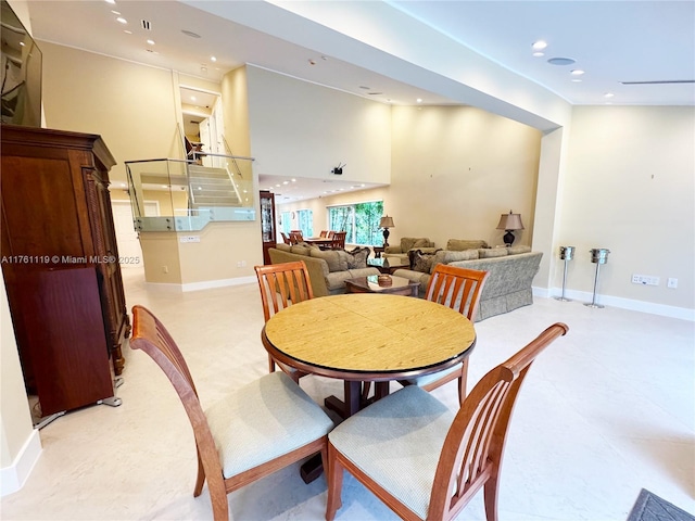 dining area featuring recessed lighting, baseboards, a high ceiling, and stairs