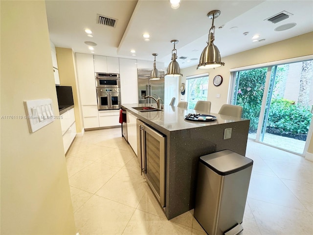 kitchen with wine cooler, visible vents, appliances with stainless steel finishes, and a sink