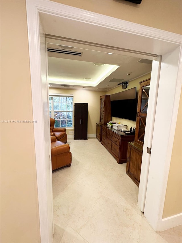 hallway featuring light floors, a tray ceiling, and baseboards