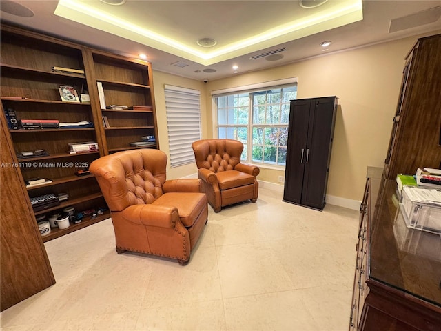 living area with baseboards, a raised ceiling, and visible vents