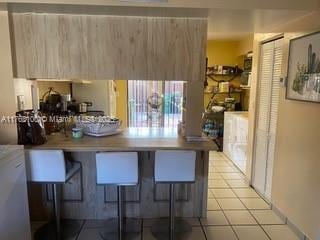 kitchen with light tile patterned floors, a peninsula, modern cabinets, and a breakfast bar