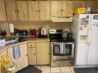 kitchen featuring under cabinet range hood, light brown cabinetry, light tile patterned floors, electric stove, and white fridge with ice dispenser